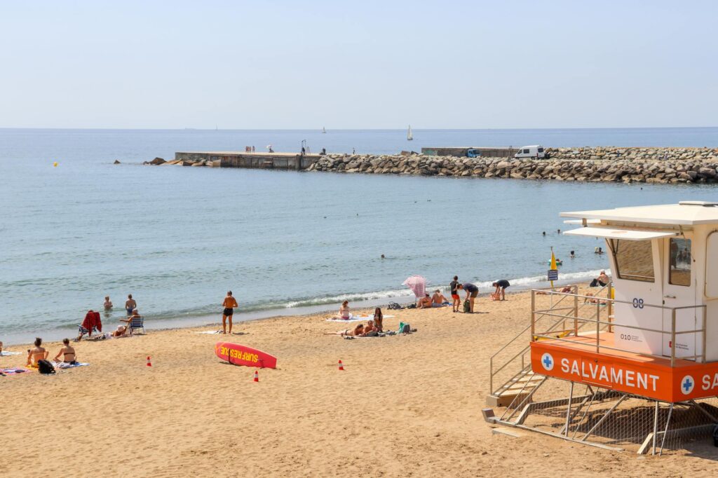 Panoramic view of Barceloneta Beach in Barcelona with lifeguard tower and sunbathers on a sunny day